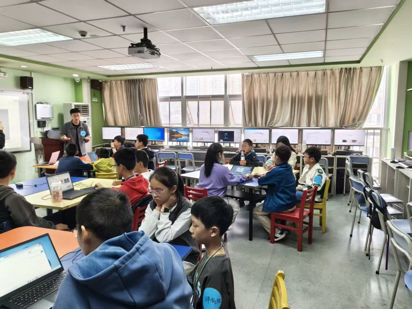 DemoDay 现场，学员分组用电脑做作品，教练在前方讲解